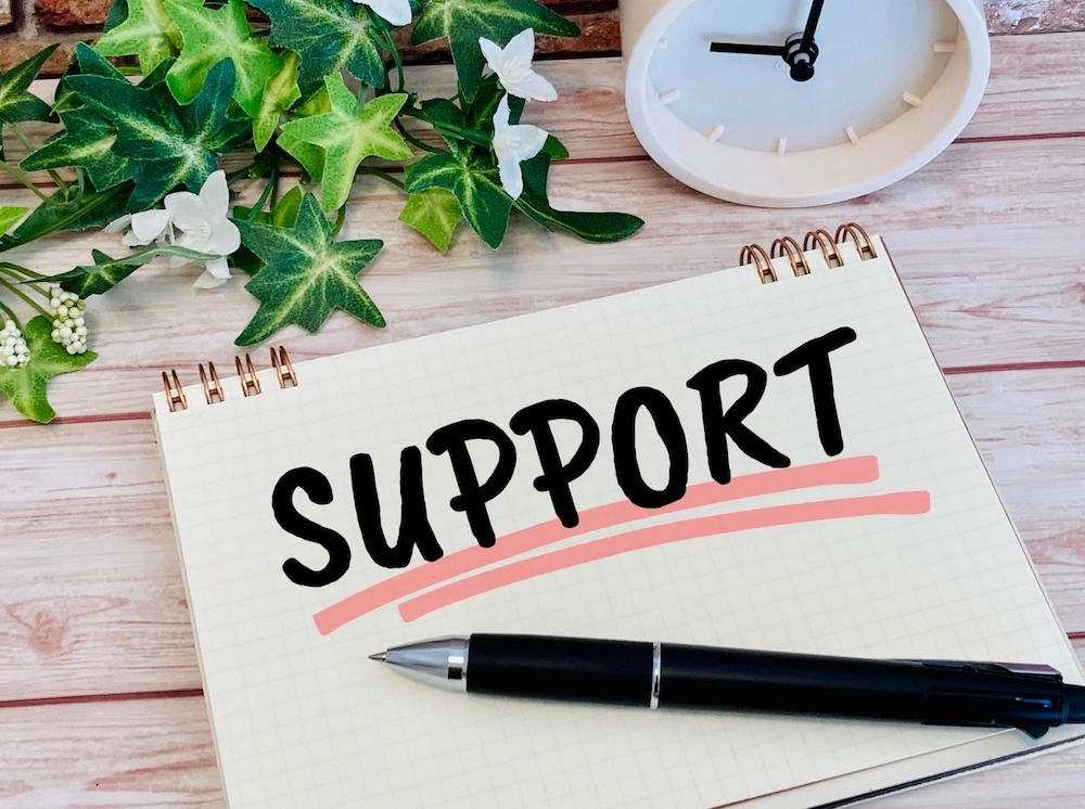 「SUPPORT」と書かれたメモ帳とペン